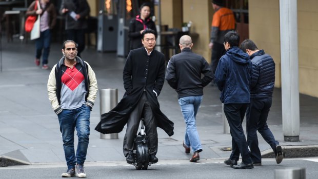 A man rides his airwheel through the streets of Sydney.