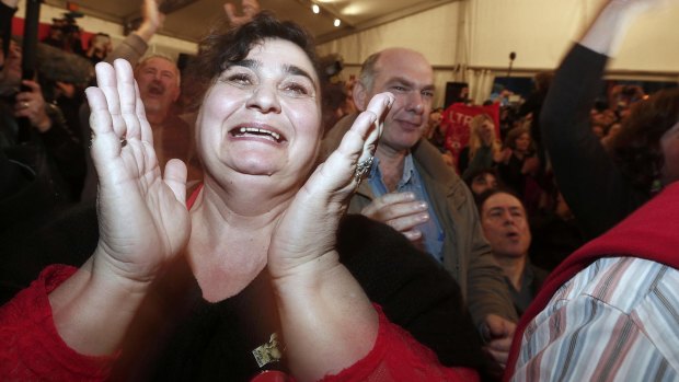 A Syriza party supporter cheers as exit polls announce that party leader Alexis Tsipras is on the brink of victory.