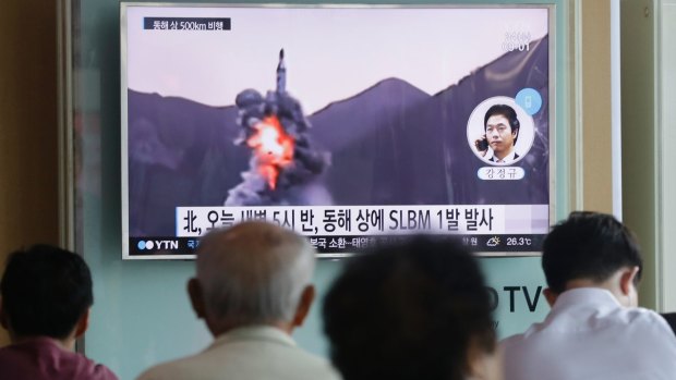 People watch a TV news program showing a file footage of North Korea's ballistic missile that the North claimed to have launched from underwater, at Seoul Railway station.