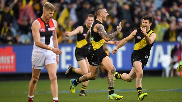 Running wild: Tigers celebrate a Dustin Martin goal, as retiring St Kilda club champion Nick Riewoldt's gets set for a centre bounce.