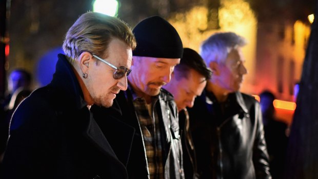 Bono and band members of U2 pay their respects and place flowers on the pavement near Bataclan Concert Hall.