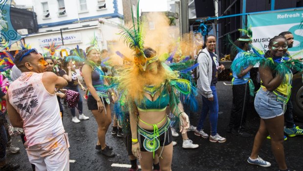 A performer has powder paint thrown at her face at the Notting Hill Carnival in London, England. 