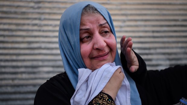 A woman weeps with relief as she waits to be taken to a displaced people's camp at a screening point in western Mosul.