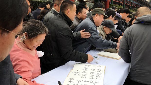 People sign the visitors' book before paying their respects to Li Zhao.