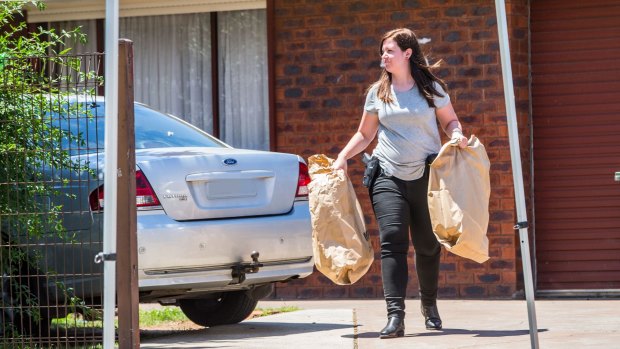 A police officer carries evidence from a house in Werribee on Tuesday.