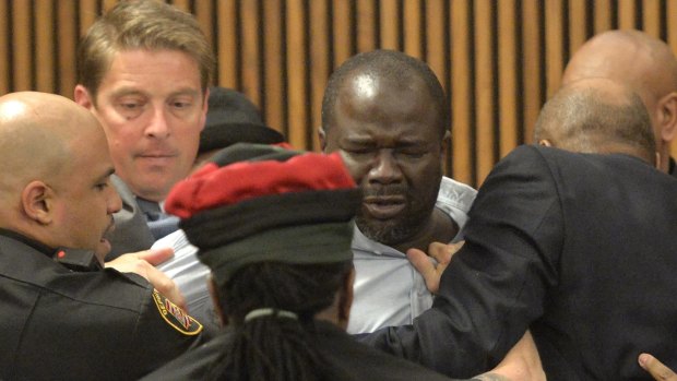 Court officers escort Van Terry, centre, from the courtroom after he dived across a courtroom table to attack convicted serial killer Michael Madison.