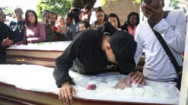 Samuel mourns over the casket of his grandmother Marlene Maria Conceicao who along with her daughter Ana Cristina was killed in a crossfire on Monday.