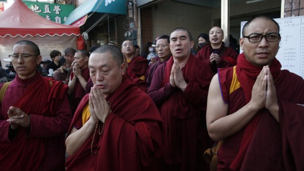Tibetan monks pray for the missing people said to be still inside the collapsed building complex in Tainan, Taiwan, on Sunday.