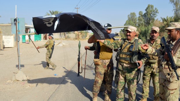 Iraqi soldiers take down an IS flag outside Ramadi on Monday.