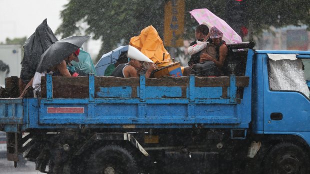 Filipinos riding on a truck take cover in Manila, Philippines on Monday as Typhoon Goni exits the country.