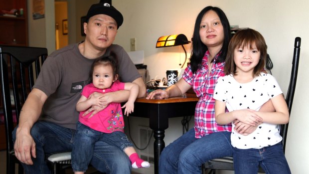 Adam Crapser, left, with daughters Christal, one, Christina, five, and his wife, Anh Nguyen, in the family's living room in Vancouver, Washington state.