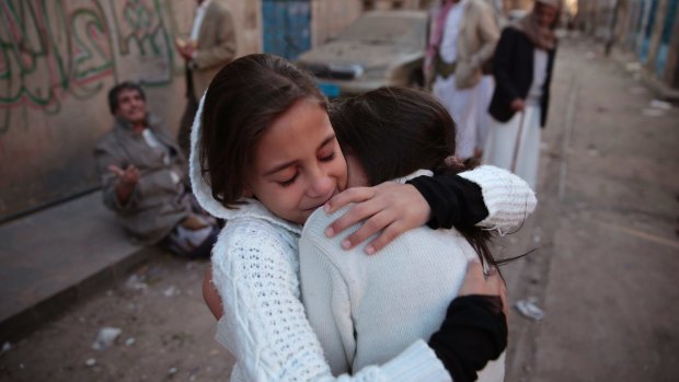 Girls react as they stand near their house which was damaged by a Saudi-led airstrike last Saturday.