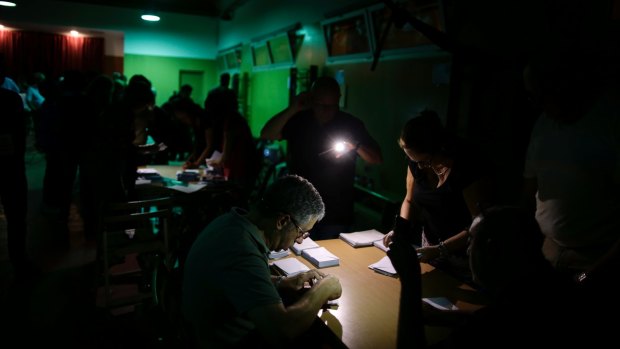 Officials use mobile phone lights to count votes during a power outage at a school assigned to be a polling station by the Catalan government in Barcelona, Spain.