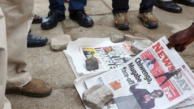 Zimbabweans check newspapers as armed soldiers patrol the streets in Harare.