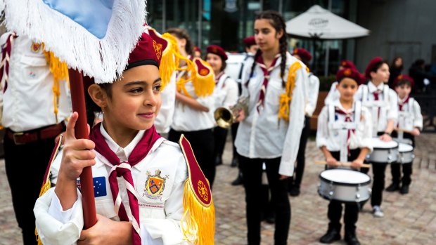 Proud new Aussie: Flag bearer Farah, 9, leads the Australian Syrian Youth Marching Band around Federation Square.