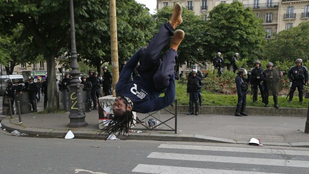 A protester does a somersault in front of a line of police during a demonstration in Paris on Thursday.
