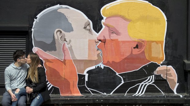 A couple kiss in front of graffiti depicting Russian President Vladimir Putin, left, and Republican presidential candidate Donald Trump, on the wall of a bar in the old town in Vilnius, Lithuania.