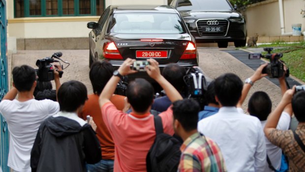 Journalists gather at the gate of the North Korean Embassy as vehicle manoeuvers in the driveway.