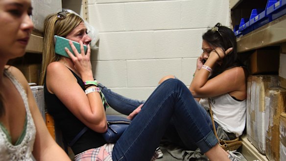 Women make phone calls while taking shelter inside the Sands Corporation plane hangar after the mass shooting in Las Vegas.
