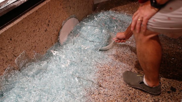 A volunteer helps clean up broken glass after a violent crowd broke windows on many businesses after clashing with police in University City, Missouri. 