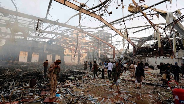 People inspect the aftermath of an air strike in the Yemeni capital, Sanaa, which killed at least 100 people and injured hundreds more.