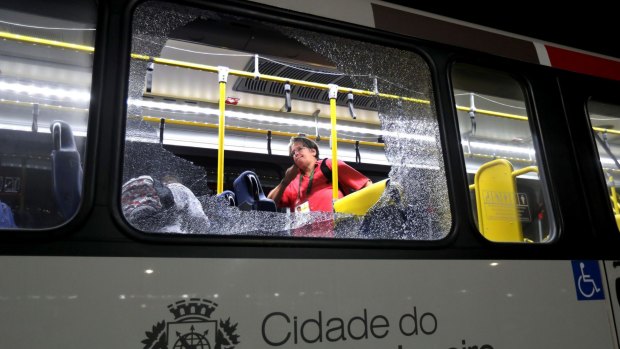 A member of the media stands near a shattered window on a bus in the Deodoro area of Rio de Janeiro after it came under attack.