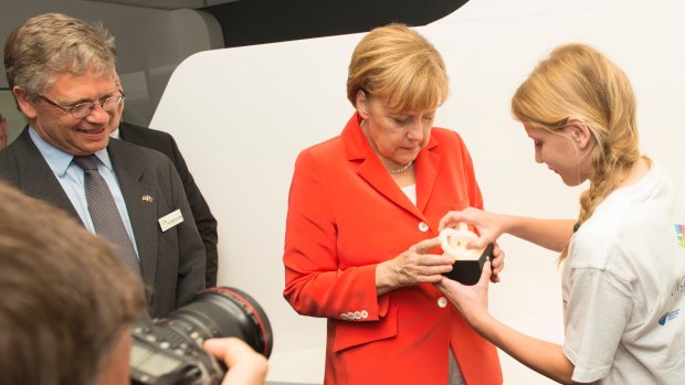 German Chancellor Angela Merkel tries out Esther Schulz's mood light as NICTA CEO Hugh Durrant-Whyte looks on.