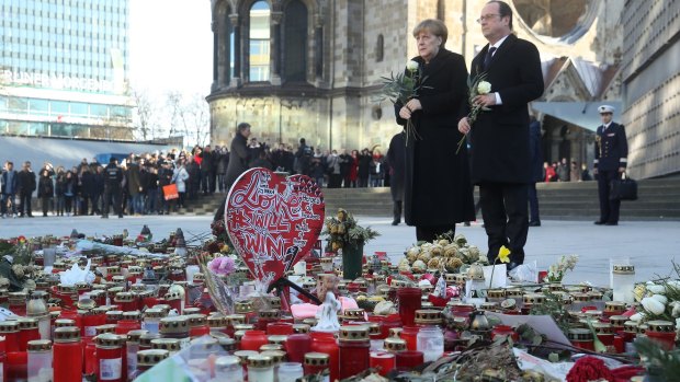 French President Francois Hollande and German Chancellor Angela Merkel prepare to lay flowers at a memorial to the victims of the December Berlin terror attack at Breitscheidplaz in Berlin, Germany. 