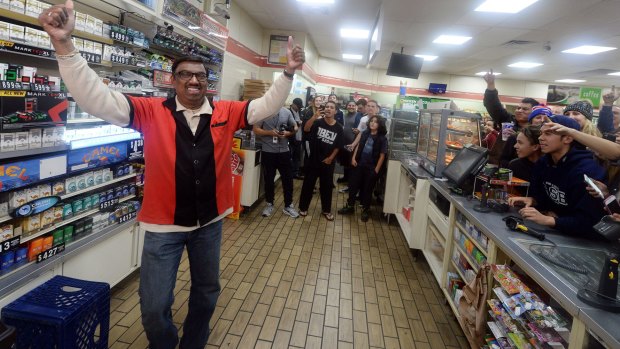 7-Eleven store clerk M Faroqui celebrates after learning the store sold a winning Powerball ticket.