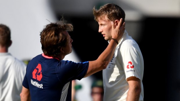 Bounced: Joe Root is checked out after being hit in the helmet at the Gabba.