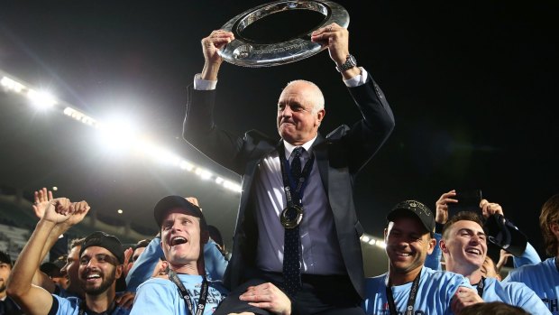 Graham Arnold is hoisted by players with the A-League trophy.
