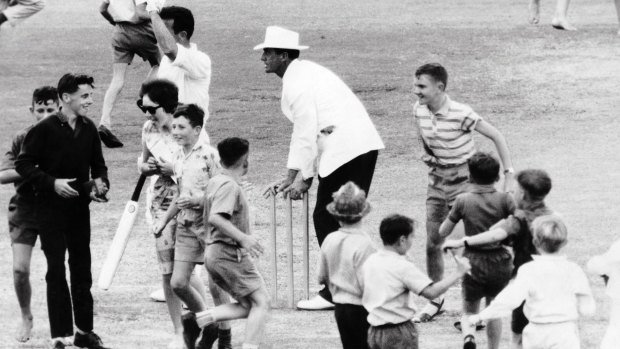 Lou Rowan stops children from taking the stumps after they ran on the field during Third Test between England and Australia at the SCG, 1963.