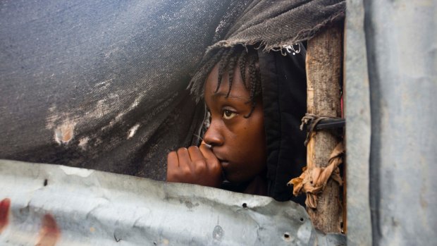 A girl watches as authorities evacuate people from her house in Tabarre, Haiti, on Monday.