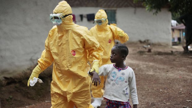 Hand and glove: Nine-year-old Nowa Paye is taken to an ambulance after showing signs of Ebola infection in the village of Freeman Reserve, about 50 kilometres north of Monrovia, Liberia.