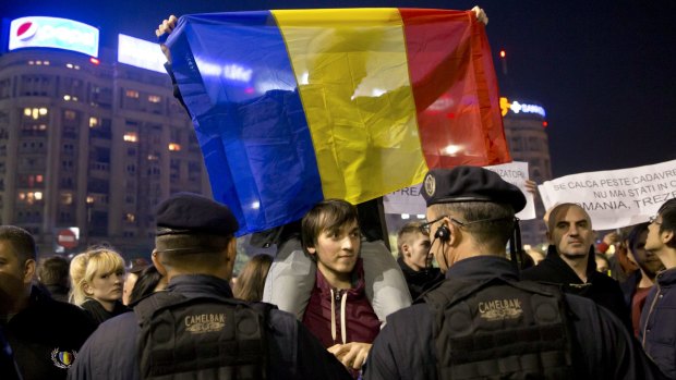 A man holds a Romanian flag during a protest in Bucharest, Romania, early on Tuesday.