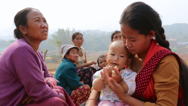 'We don't even know which side he's fighting on': Jin Ernan (right) and her 11-month-old daughter with other women at a refugee camp  in Yunnan Province.