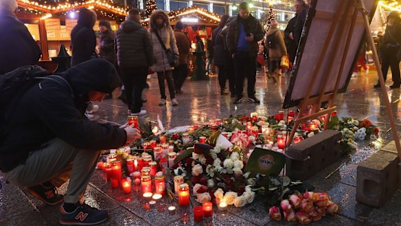  A visitor lays a candle at a makeshift memorial inside the reopened Breitscheidplatz Christmas market.