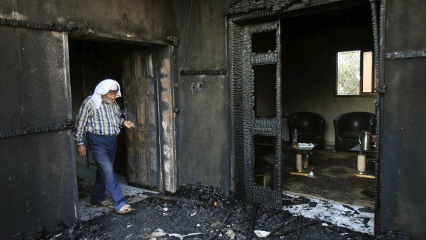 A Palestinian man inspects the remains of the Dawabshes' home. Three members of the family were critically injured.