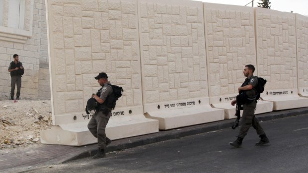 Israeli border policemen walk by the barrier being built between Palestinian and Jewish neighbourhoods in Jerusalem.