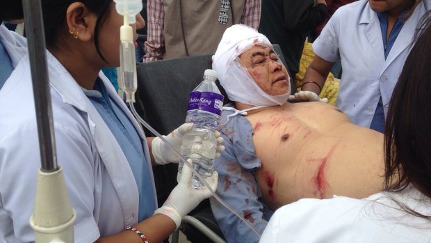 An Injured person receives treatment outside the Medicare Hospital in Kathmandu, Nepal.