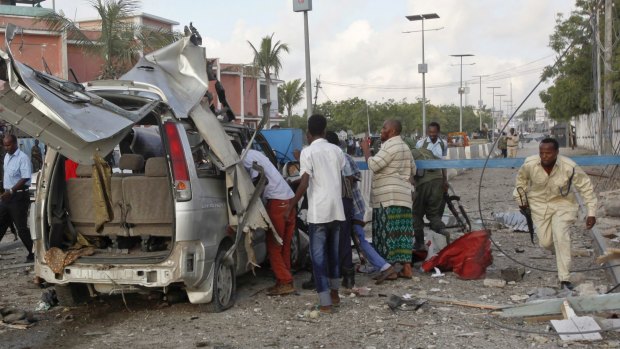 A Somali policeman runs through the wreckage outside the Sahafi Hotel in Mogadishu, Somalia.