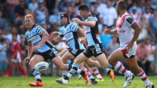Luke Lewis and Michael Ennis of the Sharks watch on as Chad Townsend of the Sharks kicks ahead during the round two match between the Cronulla Sharks and the St George Illawarra Dragons 
