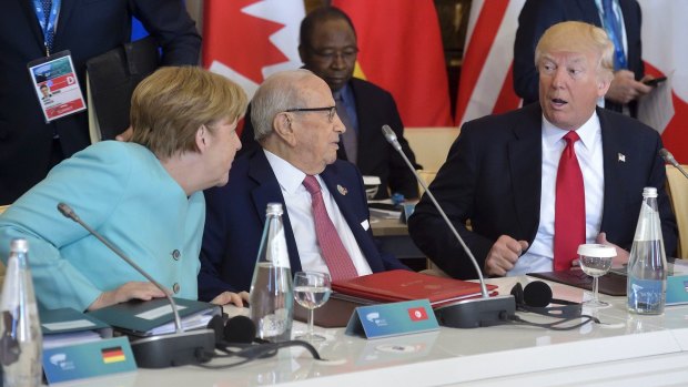 US President Donald Trump shares a word with German Chancellor Angela Merkel as Tunisia's President Beji Caid Essebsi, centre, listens at a G7 Summit expanded session on Saturday.
