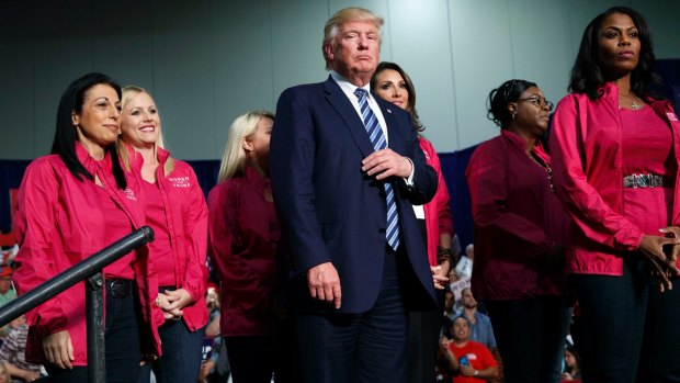 Republican presidential candidate Donald Trump stands on stage with female supporters during a campaign rally North Carolina.