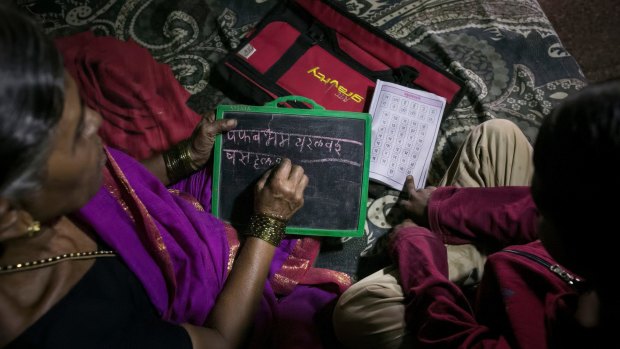 7-year-old Sujal, right, helps his grandmother, Kanta More, 65, with her schoolwork. 