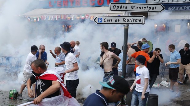 England supporters take evasive action after French police fired tear gas at them in downtown Marseille, France.