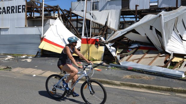 A resident cycles past a cyclone damaged business in the northern Queensland town of Rockhampton on Saturday.
