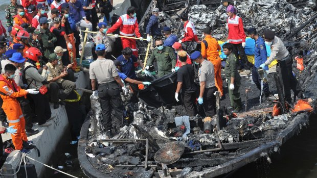 Rescuers search for victims from the wreckage of a ferry that caught fire off the coast of Jakarta.