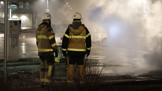 Firefighters keep watch over the riot. in the Stockholm suburb of Rinkeby.