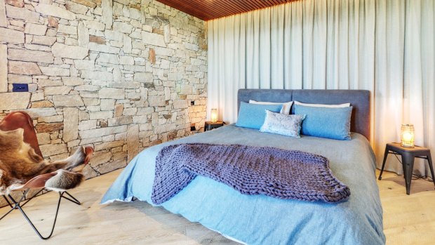 Snuggle under luxe linen in a king bed in the cosy master bedroom with a beautiful rock feature wall that evokes chalet memories. 